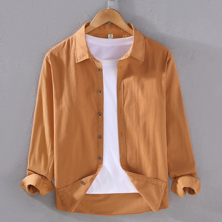 Camicia casual marrone chiaro da uomo su gruccia, con maniche lunghe e bottoni, sopra una maglietta bianca. Moda maschile, abbigliamento casual.
