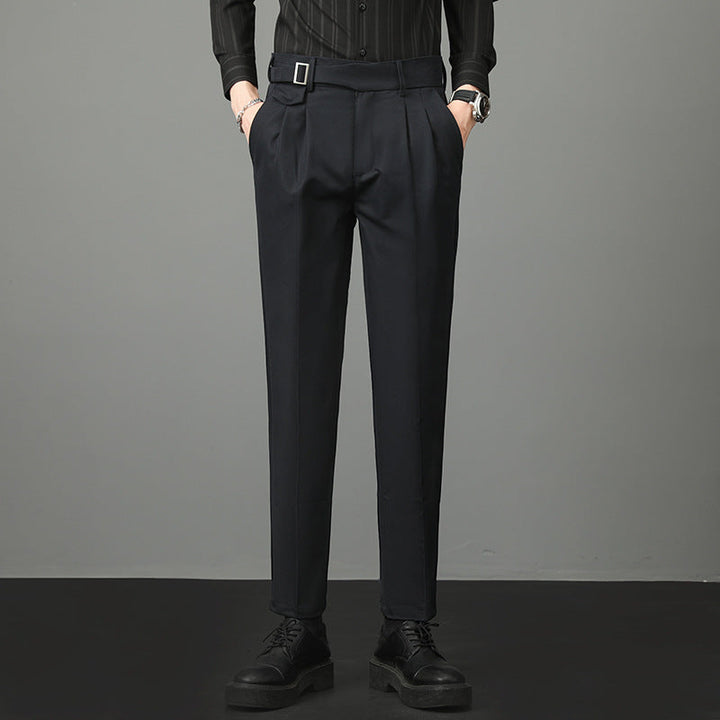 Pantaloni eleganti neri da uomo, con cintura e pieghe, abbinati a camicia scura e scarpe nere. Moda maschile formale, abbigliamento classico.