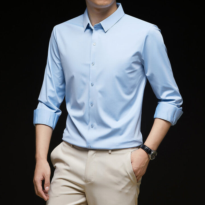 Camicia azzurra elegante da uomo con maniche lunghe arrotolate, abbinata a pantaloni beige. Stile formale, moda maschile, abbigliamento business casual.
