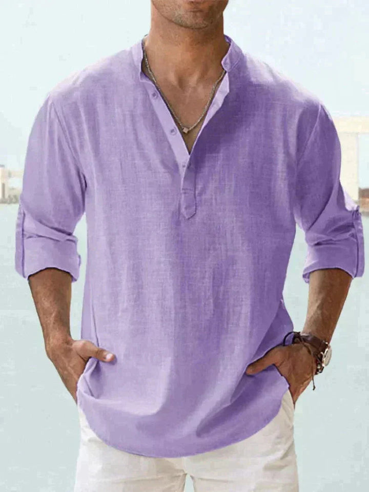 Camicia uomo lino viola, maniche lunghe arrotolate, stile casual estivo, collo alla coreana, abbinata a pantaloni bianchi.