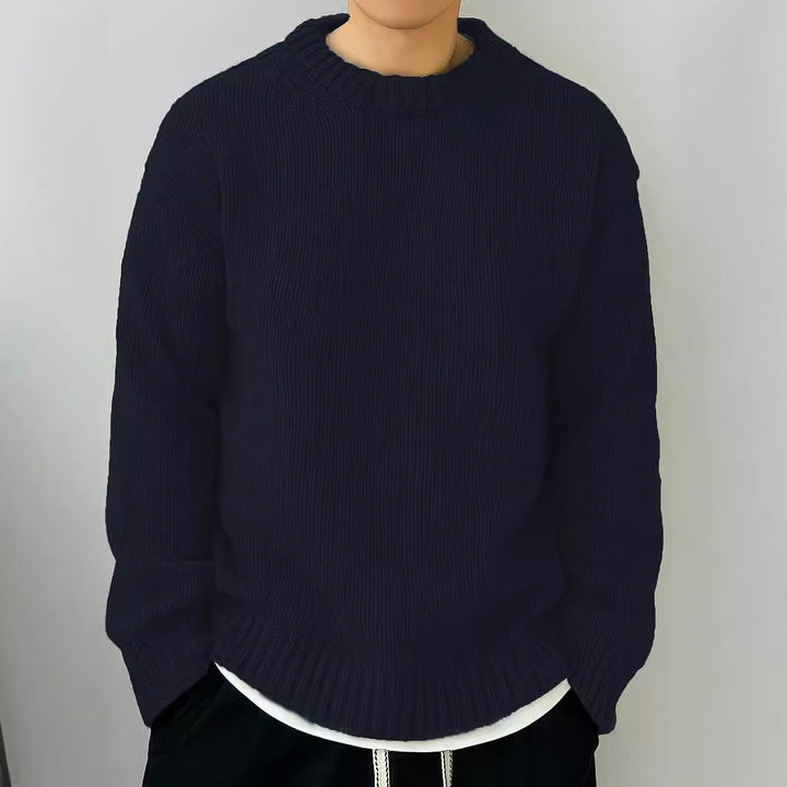 Maglione uomo blu scuro, collo rotondo, stile casual, indossato su pantaloni neri. Moda autunnale, abbigliamento maschile elegante e confortevole.
