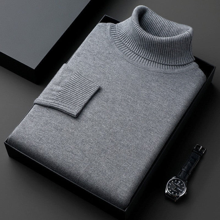 Maglione dolcevita grigio piegato in scatola nera, accanto a orologio da polso elegante. Moda uomo, abbigliamento invernale, stile classico.