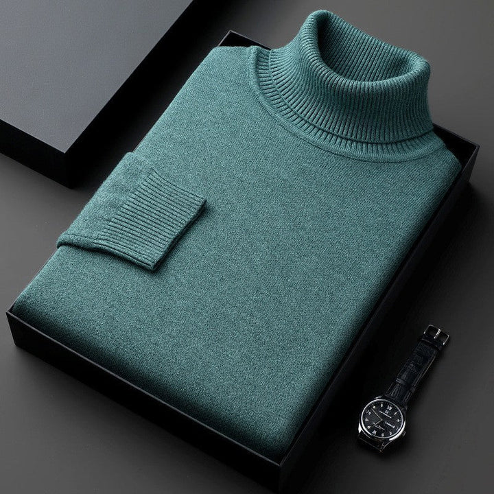 Maglione dolcevita verde piegato in scatola nera, accanto a orologio da polso elegante. Moda uomo, abbigliamento invernale, stile sofisticato.