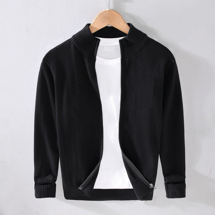 Cardigan nero aperto con zip, su gruccia, sopra maglietta bianca. Moda uomo, abbigliamento casual, stile autunnale.