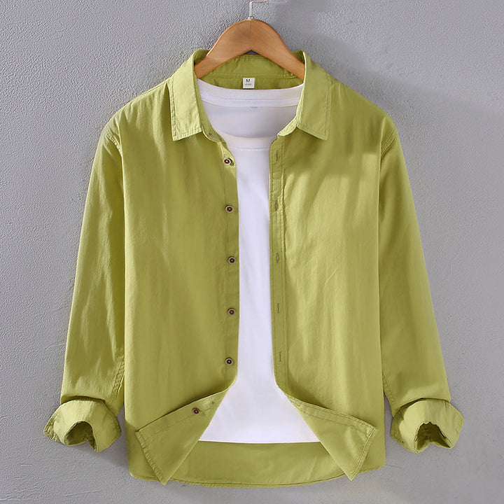 Camicia verde chiaro da uomo su gruccia, con colletto classico e maniche lunghe, abbinata a t-shirt bianca. Moda casual, abbigliamento maschile.