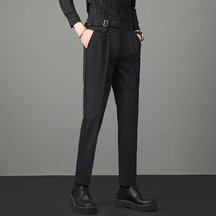 Pantaloni eleganti neri da uomo, con cintura e pieghe, abbinati a camicia nera e scarpe in pelle. Moda maschile, abbigliamento formale.