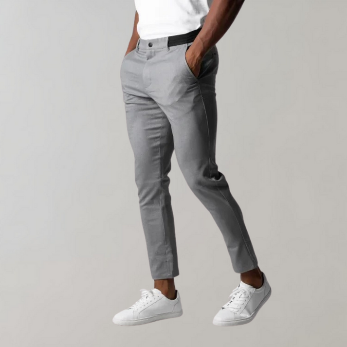 Pantaloni chino grigi da uomo, eleganti e moderni, abbinati a scarpe da ginnastica bianche e maglietta bianca. Moda casual maschile.