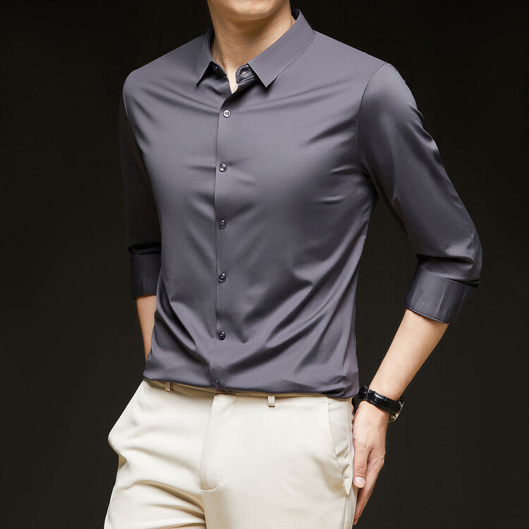 Camicia uomo grigia elegante a maniche lunghe, abbinata a pantaloni beige. Moda maschile, abbigliamento formale, stile moderno.