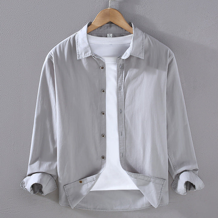 Camicia grigia da uomo in cotone, maniche lunghe, su gruccia. Design casual, abbinata a t-shirt bianca. Moda maschile, abbigliamento elegante.