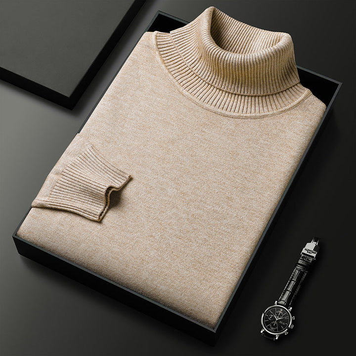 Maglione dolcevita beige in cashmere piegato in scatola nera su sfondo scuro, accanto a orologio elegante. Moda uomo, abbigliamento invernale di lusso.
